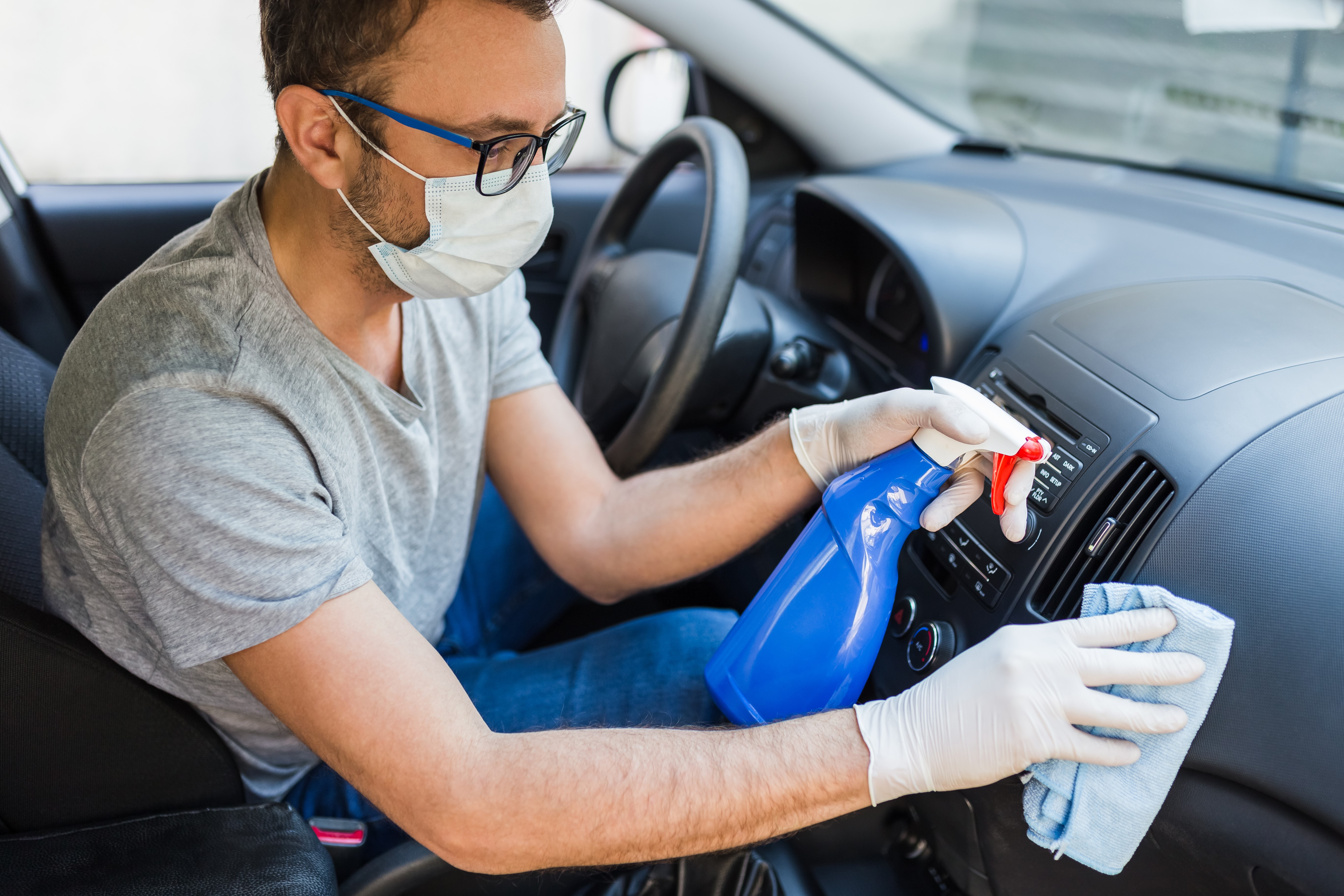 Man Cleaning the Interior of a Car with a Mask on